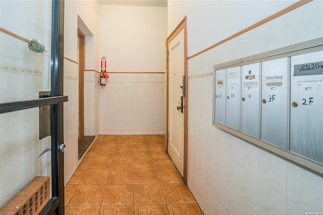 hallway with mail boxes and tile walls