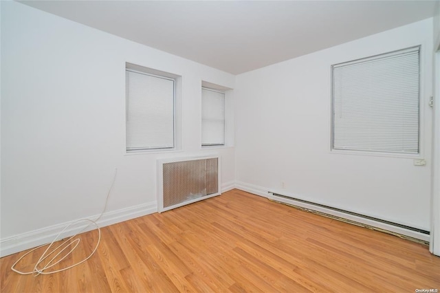 empty room featuring radiator heating unit, a baseboard radiator, and wood-type flooring