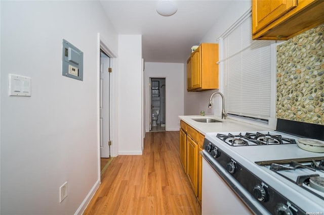 kitchen with light wood-type flooring, sink, and white range with gas cooktop