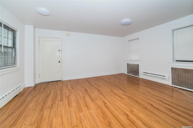 unfurnished living room featuring radiator heating unit, light hardwood / wood-style floors, and baseboard heating