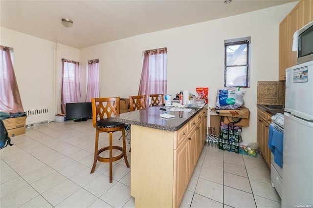 kitchen with radiator, a wealth of natural light, light brown cabinets, white appliances, and a breakfast bar