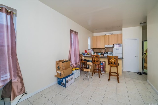 kitchen featuring backsplash, a breakfast bar, light brown cabinets, light tile patterned floors, and fridge