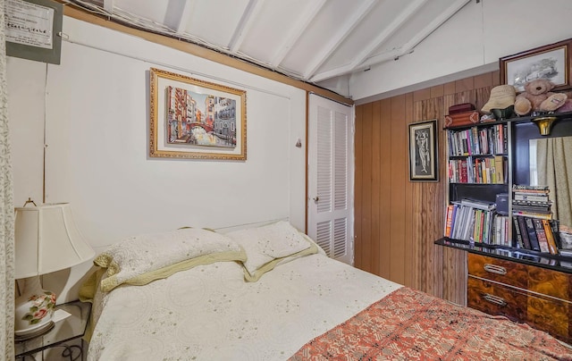 bedroom with a closet, wood walls, and lofted ceiling