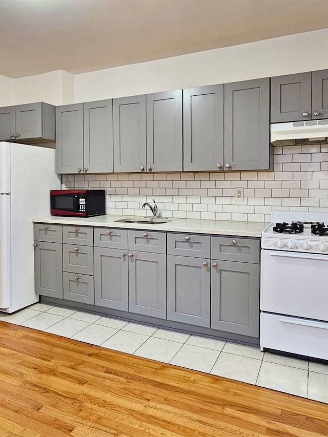 kitchen with sink, gray cabinetry, tasteful backsplash, light tile patterned floors, and white appliances