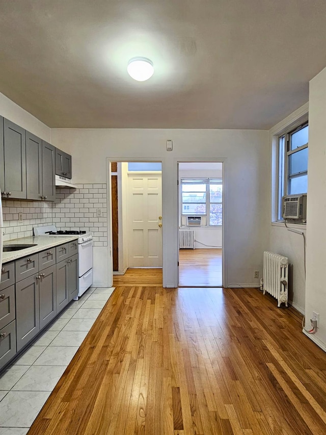 kitchen featuring gray cabinets, radiator, white range with gas cooktop, and light hardwood / wood-style floors