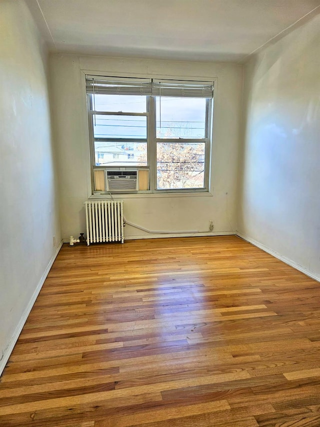 empty room with cooling unit, radiator, and light hardwood / wood-style flooring