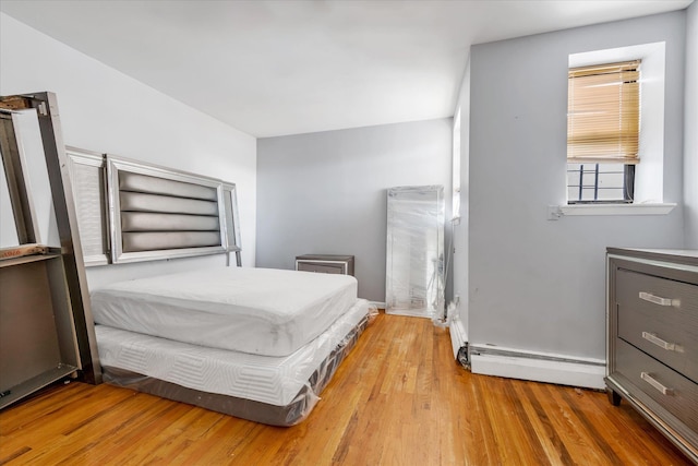 bedroom featuring wood-type flooring and a baseboard heating unit