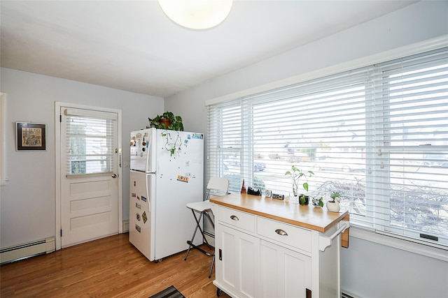 kitchen featuring white cabinets, light wood-type flooring, white fridge, and plenty of natural light