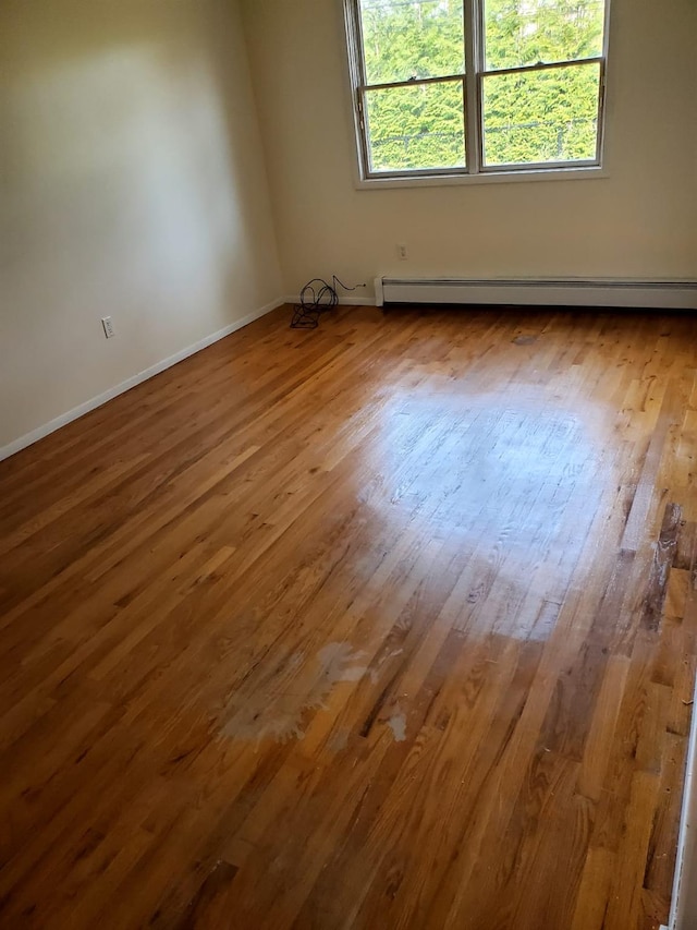 empty room featuring hardwood / wood-style flooring and baseboard heating