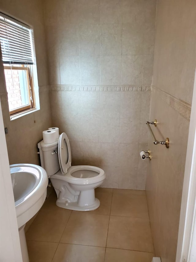 bathroom featuring tile patterned flooring, toilet, and tile walls