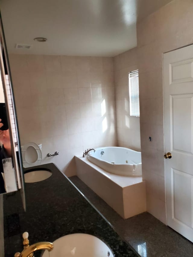 bathroom with a relaxing tiled tub, tile walls, and sink