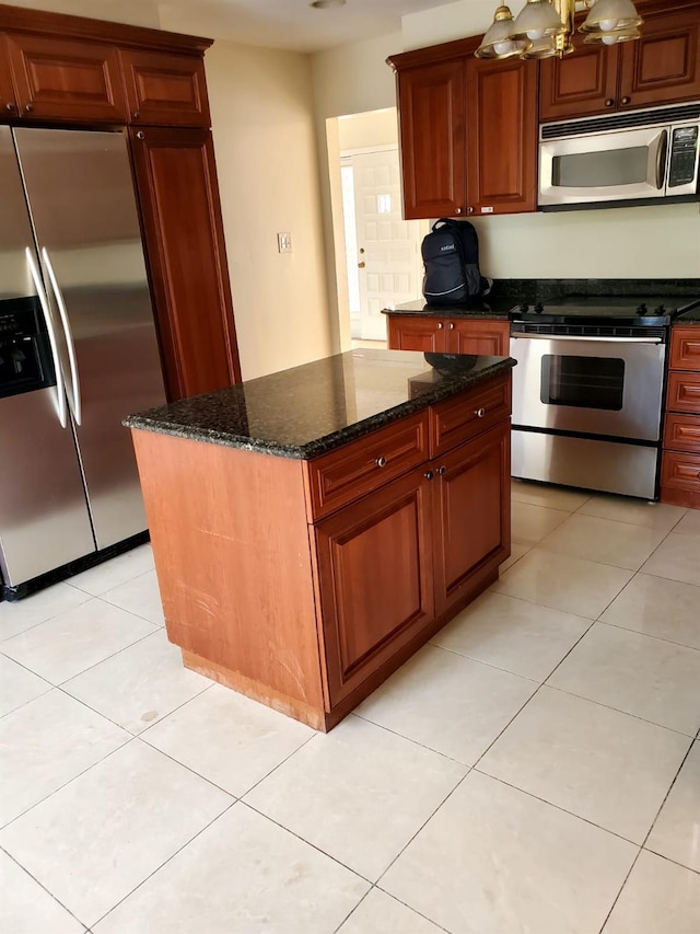 kitchen with a center island, a notable chandelier, dark stone counters, light tile patterned floors, and appliances with stainless steel finishes