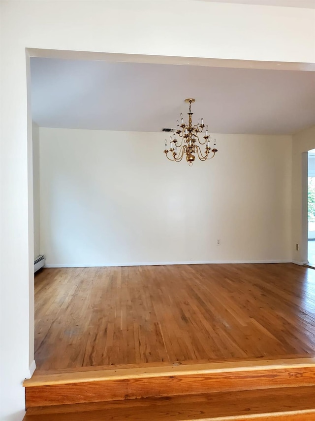 unfurnished dining area with baseboard heating, hardwood / wood-style flooring, and an inviting chandelier