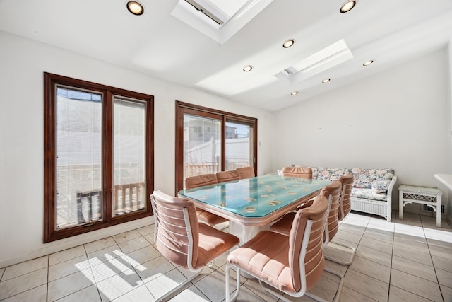 tiled dining area with vaulted ceiling with skylight