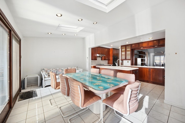 tiled dining room with sink and a skylight