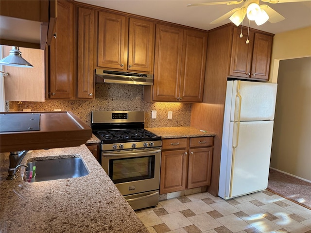 kitchen featuring tasteful backsplash, stainless steel gas stove, white refrigerator, ceiling fan, and sink