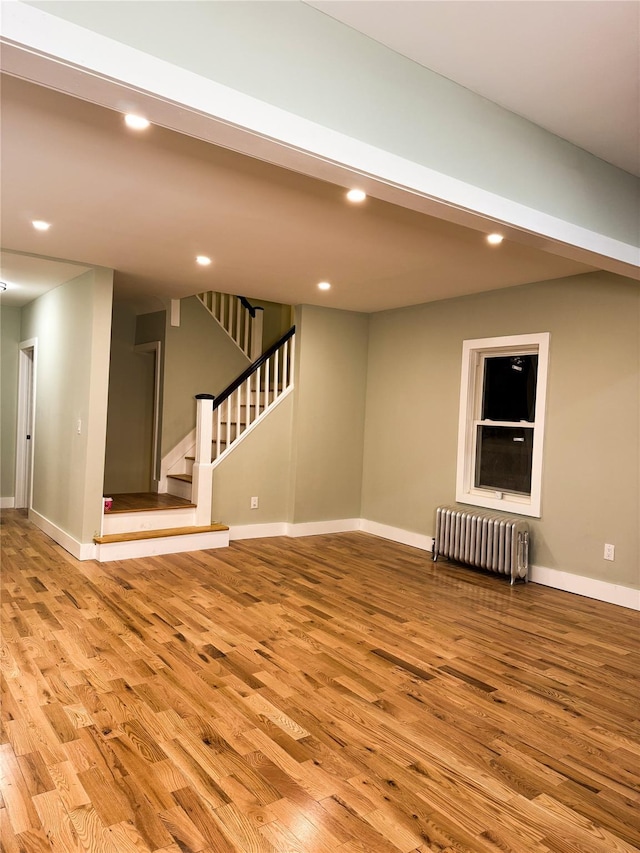 unfurnished living room featuring radiator heating unit and light hardwood / wood-style floors