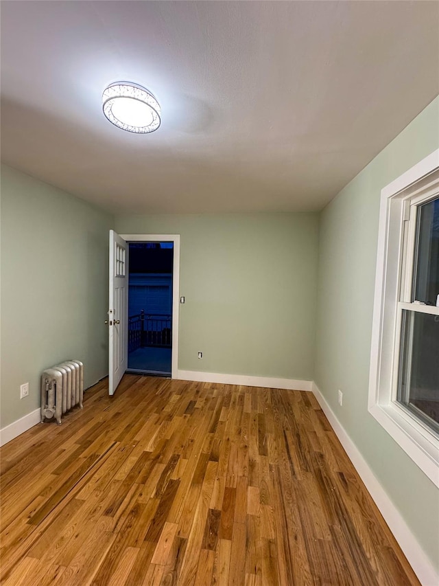 empty room with radiator heating unit and hardwood / wood-style floors