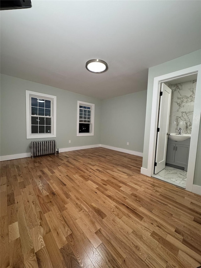 additional living space featuring light hardwood / wood-style flooring and radiator