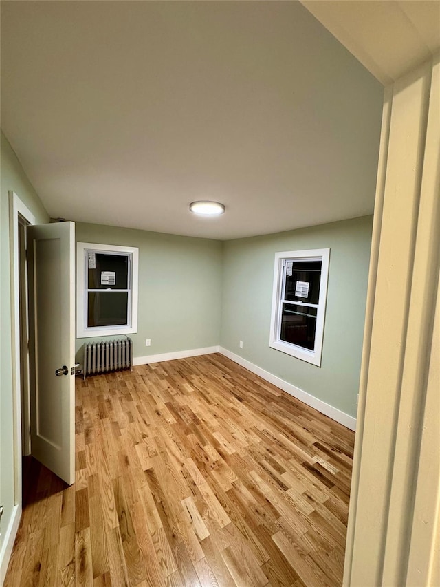 unfurnished room featuring radiator heating unit and light hardwood / wood-style flooring