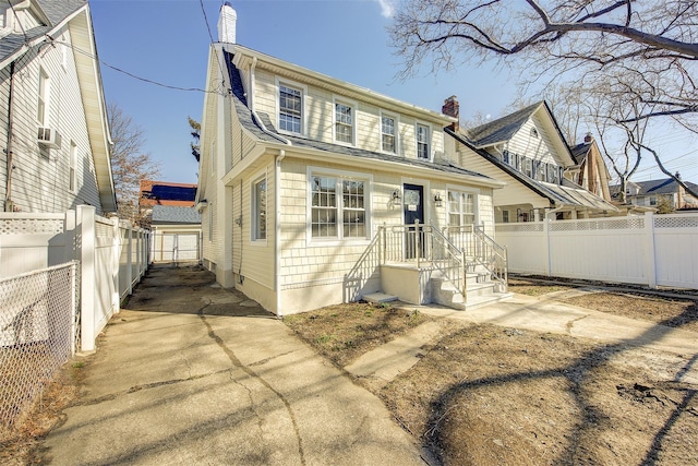 view of front of home with a chimney, fence, and concrete driveway