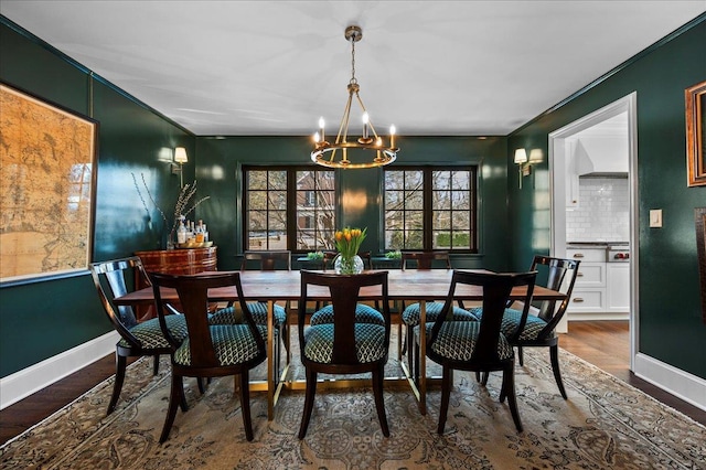 dining room with an inviting chandelier, ornamental molding, and dark wood-type flooring