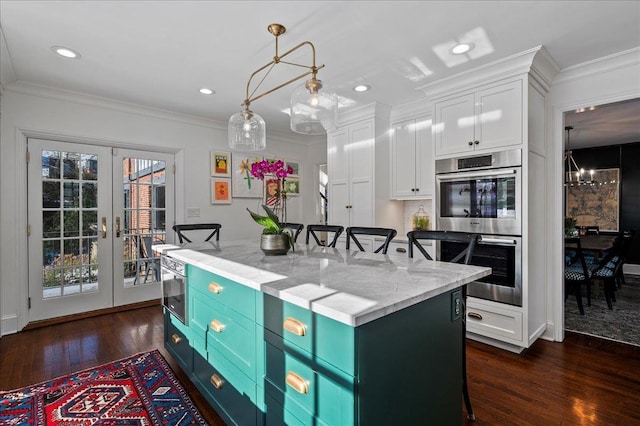 kitchen with a kitchen bar, a center island, stainless steel double oven, light stone countertops, and white cabinets