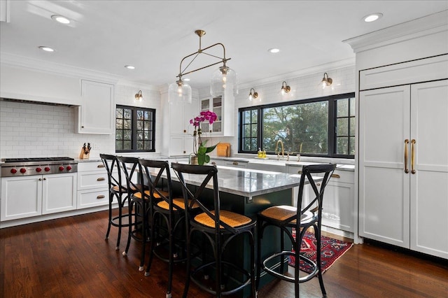 kitchen featuring backsplash, a center island, ornamental molding, white cabinets, and stainless steel gas stovetop