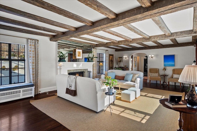 living room featuring beam ceiling, hardwood / wood-style flooring, radiator, and a high end fireplace