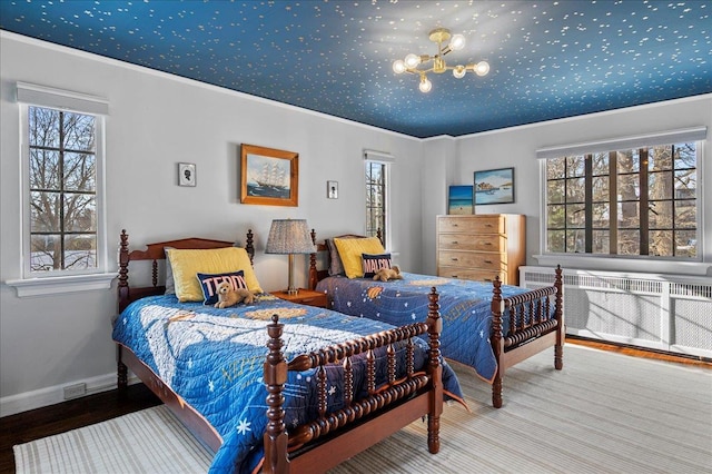 bedroom featuring ornamental molding, radiator, hardwood / wood-style floors, and multiple windows