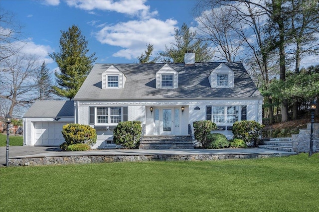 cape cod house with brick siding, a chimney, aphalt driveway, an attached garage, and a front yard