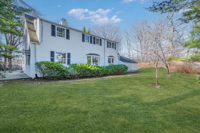 colonial inspired home featuring a chimney and a front lawn