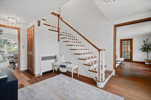 stairs featuring baseboards, hardwood / wood-style floors, and radiator