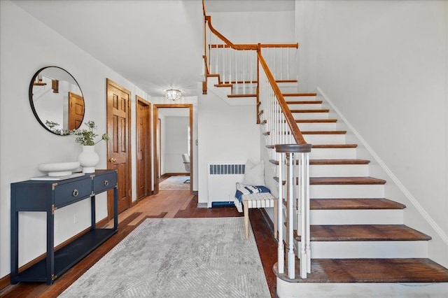 stairs with radiator, baseboards, and wood finished floors