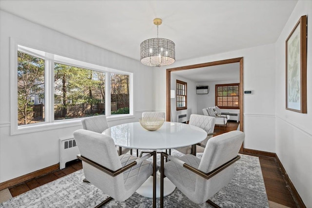 dining space featuring dark wood-style floors, radiator heating unit, a chandelier, a wall mounted air conditioner, and baseboards