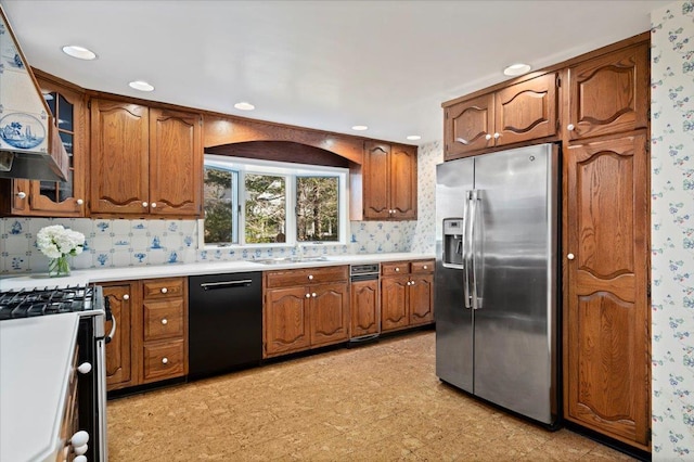 kitchen featuring appliances with stainless steel finishes, light countertops, brown cabinets, and wallpapered walls