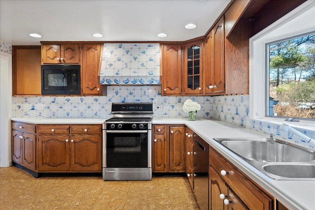 kitchen featuring black appliances, brown cabinets, a sink, and light countertops