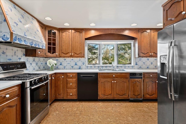 kitchen with light countertops, appliances with stainless steel finishes, a sink, and range hood