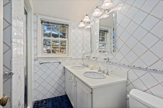 bathroom featuring a sink, tile walls, toilet, and double vanity