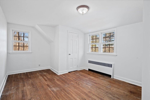 additional living space with lofted ceiling, radiator, baseboards, and hardwood / wood-style floors