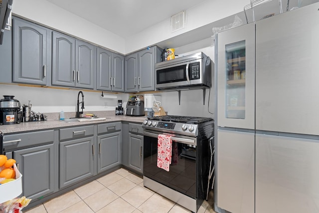 kitchen with light tile patterned floors, stainless steel appliances, gray cabinetry, and sink