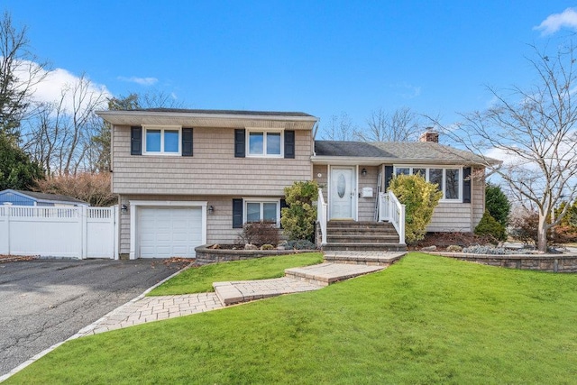 split level home featuring a garage and a front lawn