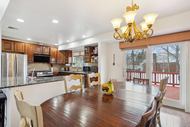 dining space featuring light wood-type flooring, an inviting chandelier, and sink