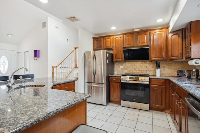 kitchen featuring sink, dark stone countertops, tasteful backsplash, light tile patterned flooring, and stainless steel appliances