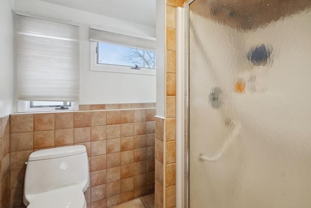 bathroom with toilet, tile walls, and a shower with shower door