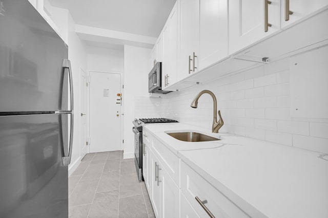 kitchen with white cabinetry, sink, stainless steel appliances, tasteful backsplash, and light tile patterned floors