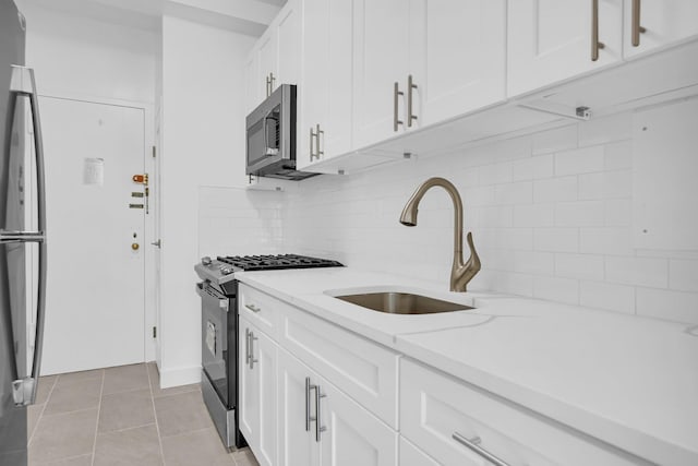 kitchen with light stone countertops, appliances with stainless steel finishes, decorative backsplash, light tile patterned floors, and white cabinets