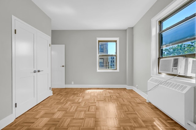 unfurnished room featuring cooling unit, radiator, and light parquet flooring