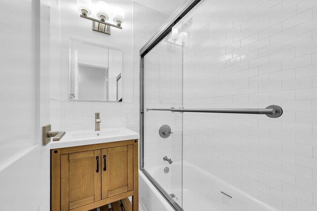 bathroom with tasteful backsplash, vanity, and bath / shower combo with glass door