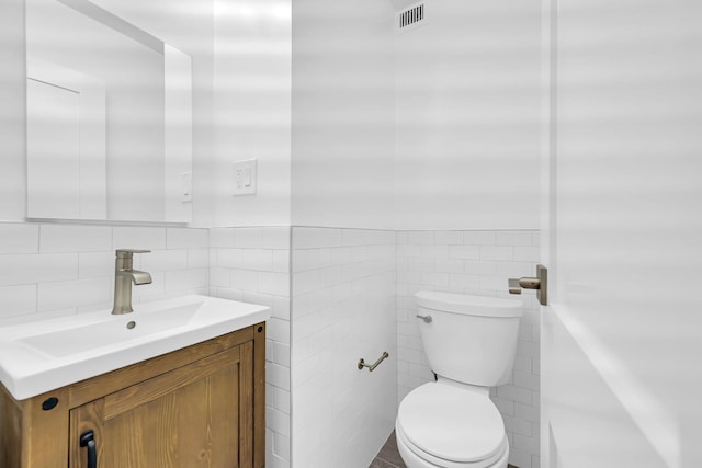 bathroom featuring vanity, toilet, and tile walls